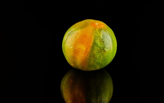 Mandarina verde amarillo madura fresca sobre negro