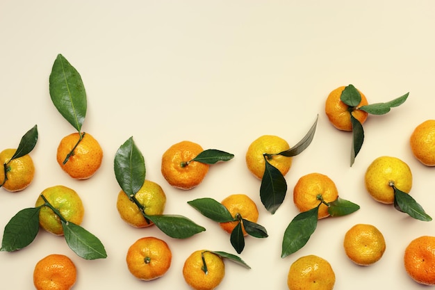 Mandarinas amarillas naranjas frescas maduras con hojas verdes en un fondo de mesa de color beige pastel con copia