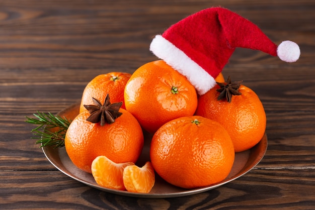 Mandarinas con anís y sombrero de Santa Claus en una mesa de madera marrón