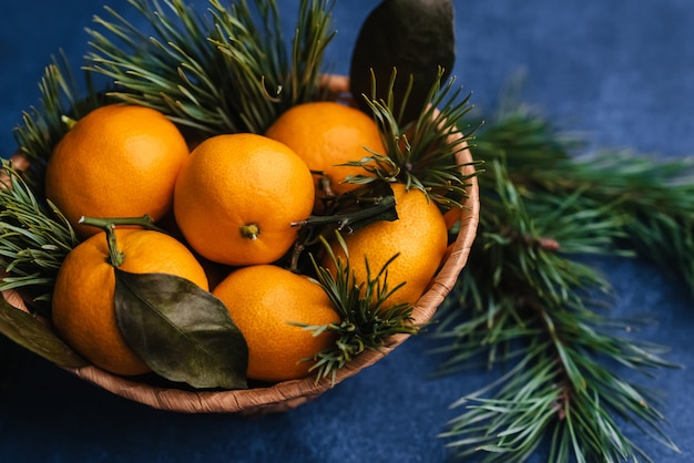 Mandarinas en cesta en mesa y árbol de navidad