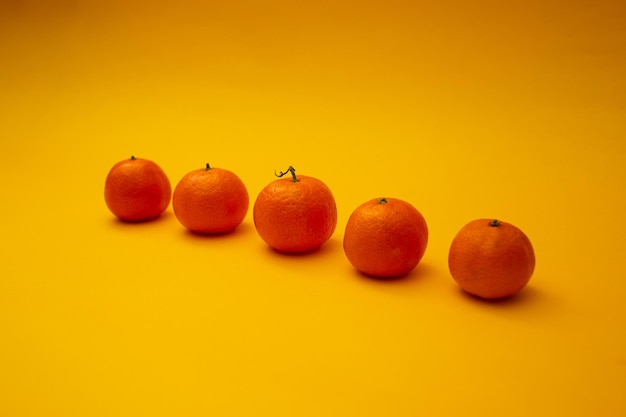 Las mandarinas de color naranja brillante yacen sobre un fondo amarillo