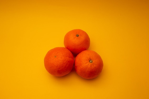 Las mandarinas de color naranja brillante yacen sobre un fondo amarillo