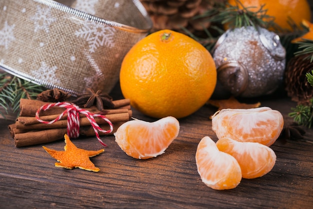 Foto mandarinas frescas con especias y decoración navideña con árbol de navidad en la mesa de madera vieja oscura. estilo rústico. concepto de vacaciones de invierno.