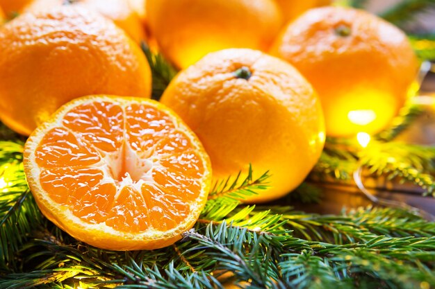 Mandarinas frescas en guirnaldas de luces, en ramas de abeto y oropel - fondo brillante de año nuevo. La mitad de una naranja, aroma cítrico de la fiesta. Navidad, año nuevo. Espacio para texto.