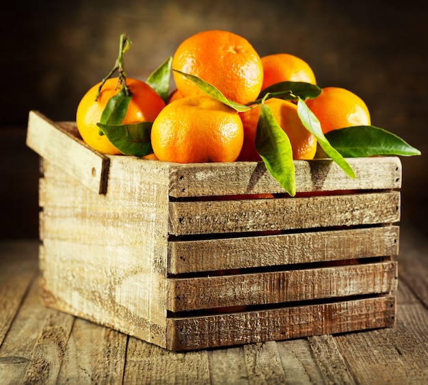 Mandarinas frescas con hojas en caja de madera