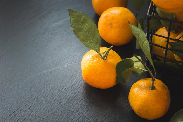 Mandarinas frescas con hojas en un tazón sobre negro Concepto de alimentación saludable Copiar espacio