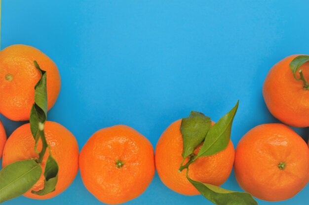 Mandarinas frutas cítricos frescos sobre un fondo azul brillante