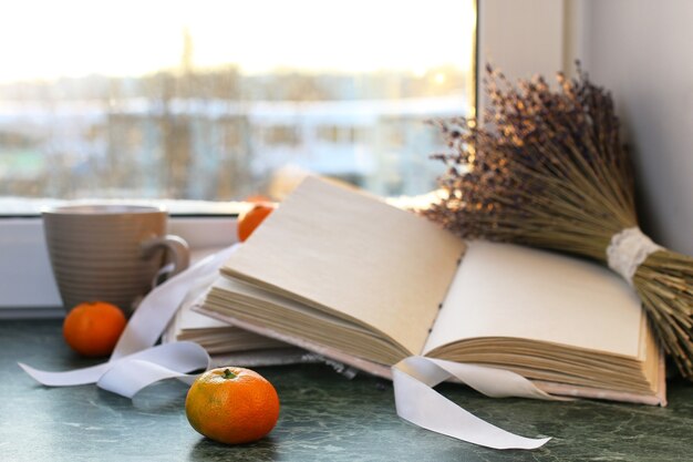 Foto mandarinas y libros antiguos sobre una mesa de mármol junto a la ventana en invierno