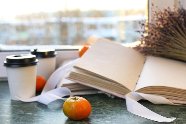 Mandarinas y libros antiguos sobre una mesa de mármol junto a la ventana en invierno