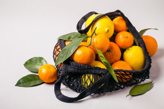 Mandarinas y limones en bolsa textil. Concepto de comida sana y cero residuos.