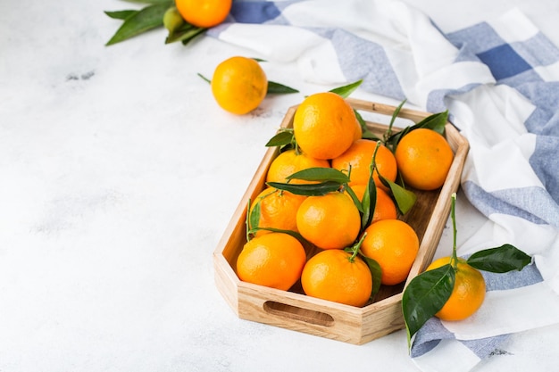 Mandarinas naranjas orgánicas frescas y jugosas mandarinas con hojas verdes en una mesa de cocina Concepto de consumo de vitaminas saludables Fondo del espacio de copia