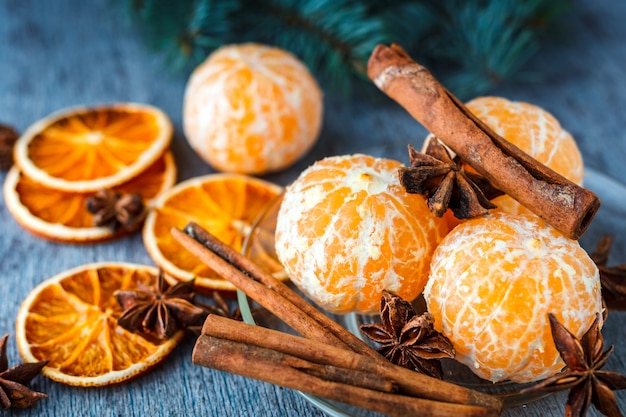 Mandarinas, naranjas secas, anís y canela en una mesa de madera junto a la rama de abeto