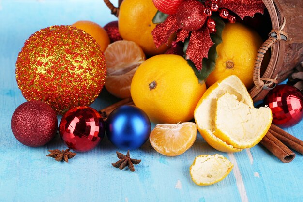 Mandarinas navideñas y juguetes navideños en canasta sobre mesa de madera sobre superficie azul