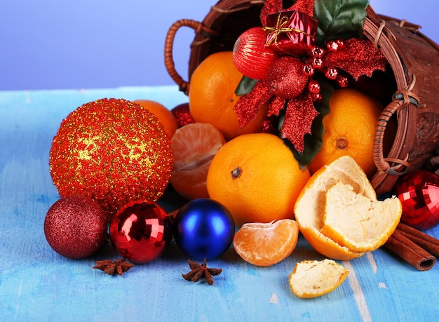 Mandarinas navideñas y juguetes navideños en canasta sobre mesa de madera