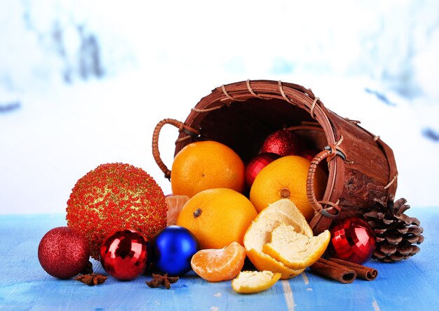 Mandarinas navideñas y juguetes navideños en la mesa de madera sobre fondo de nieve