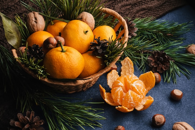 Mandarinas, nueces y avellanas decoradas con piñas y ramas.