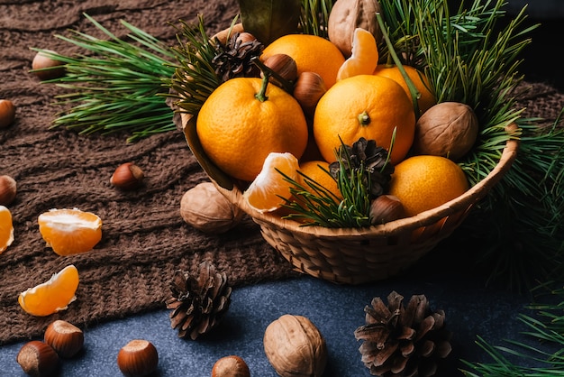 Mandarinas, nueces y avellanas decoradas con piñas y ramas.