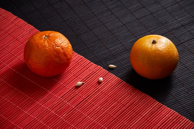 Foto mandarinas en placa sobre superficie negra y roja