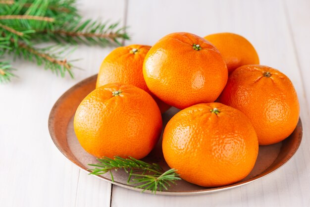 Mandarinas con ramas de abeto en una mesa de madera clara Navidad y año nuevo