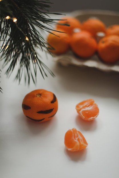 Mandarinas con rayas pintadas sobre un fondo blanco con un árbol de navidad el concepto para el nuevo ...