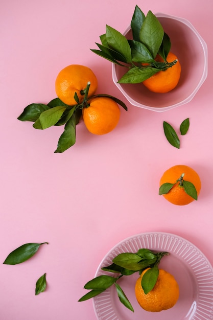 Mandarinas en un tazón rosa sobre superficie rosa