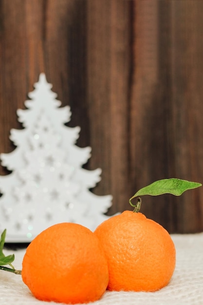 Mandarinen auf dem Hintergrund der hölzernen Weihnachtsdekorationen des neuen Jahres