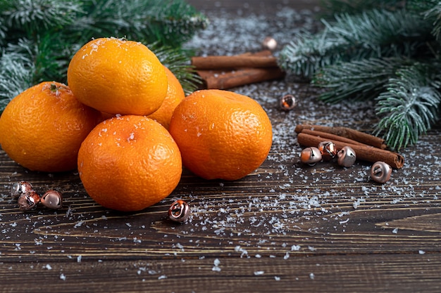 Mandarinen auf einem Holztisch mit Zweigen eines Weihnachtsbaumes bedeckt mit Schnee.