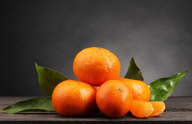 Mandarinen mit Blättern auf Holztisch auf grauem Hintergrund