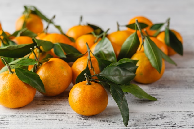 Mandarinen mit Blättern auf Holztisch. Mandarinen Mandarine Nahaufnahme. Rustikaler Stil