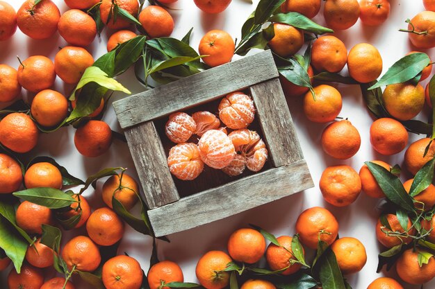 Foto mandarinen mit frischen blättern in der holzkiste lokalisiert auf weiß, lokalisiert auf einer weißen draufsicht