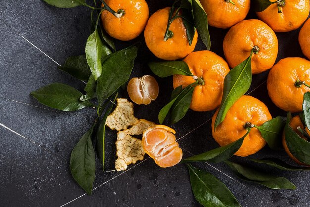 Foto mandarinen mit grünen blättern hautnah auf dunklem hintergrund