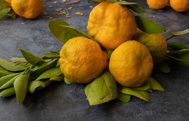 Mandarinen oder Clementinen mit grünen Blättern auf schwarzem Hintergrund