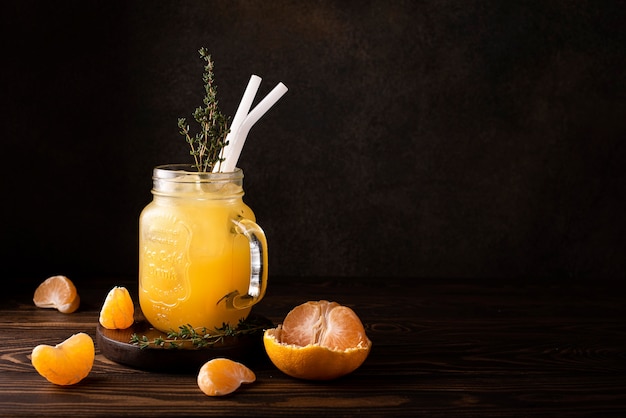 Mandarinensaft mit Eis und Thymianzweigen in einem Glasbecher