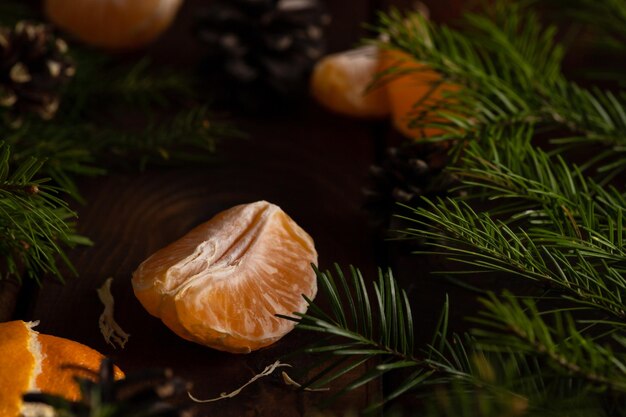 Mandarinenscheiben liegen auf einem Holztisch, umgeben von grünen Fichtenzweigen