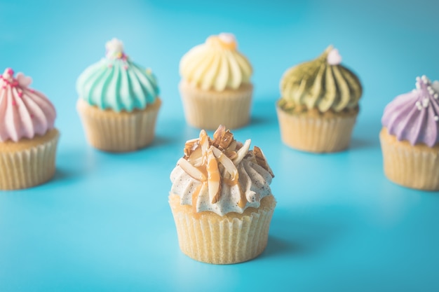 Mandel-kleiner Kuchen, der durch bunte kleine Kuchen auf blauem Hintergrund umgibt