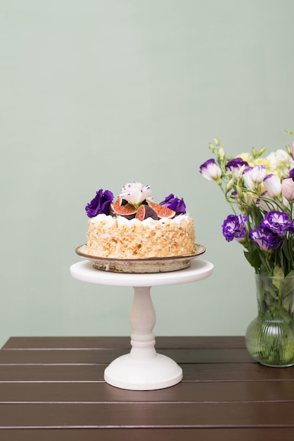 Mandelkuchen mit Feigen und Blumen auf einem rustikalen Tisch mit einem Blumenstrauß in einer Vase