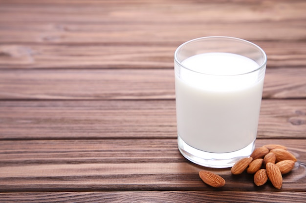 Mandelmilch im Glas mit Mandeln auf Braun