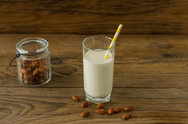 Mandelmilch im Glas mit Mandeln auf Holztisch.