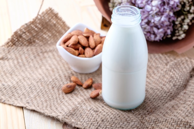 Mandelmilch in der Glasflasche auf hölzernem Hintergrund