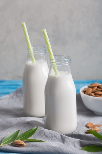 Mandelmilch in zwei Flaschen auf dem blauen rustikalen Holztisch