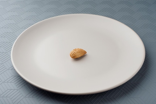 Mandeln liegen auf einem weißen Teller Grauer Tisch Gesunde Ernährung