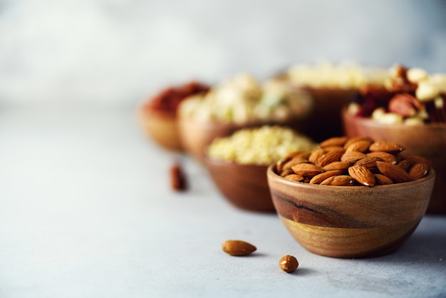 Mandelnüsse in der hölzernen Schüssel. Auswahl an Nüssen - Cashewnüssen, Haselnüssen, Mandeln, Walnüssen, Pistazien, Pekannüssen, Pinienkernen, Erdnüssen, Rosinen