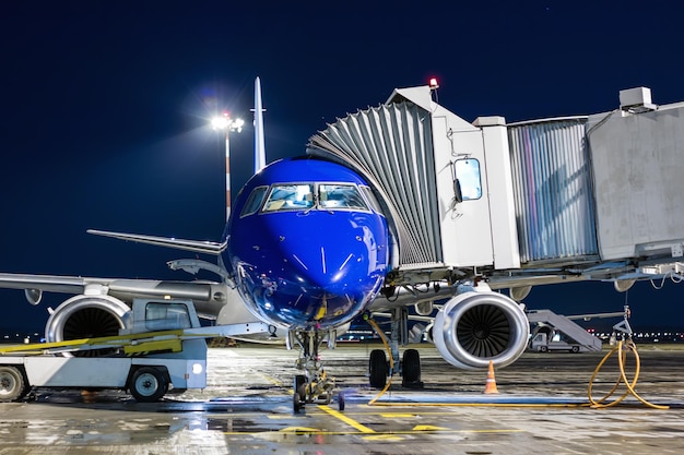 Manejo en tierra del avión cerca de una rampa de pasajeros por la noche