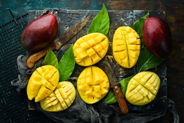 Manga doce saborosa fresca com folhas no velho fundo escuro de madeira. Estilo rústico. Vista do topo. Frutas tropicais.