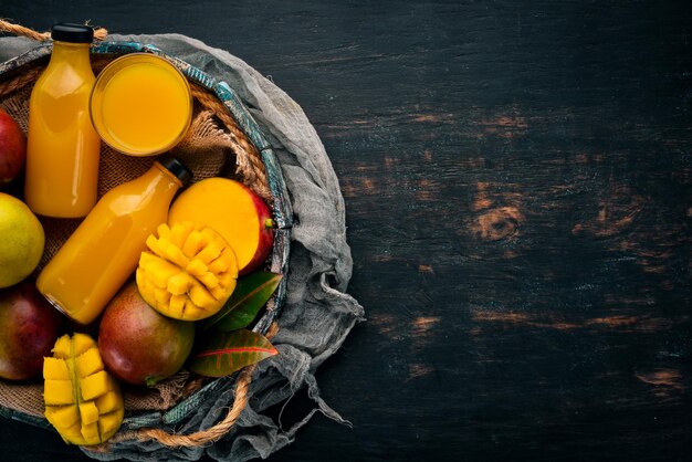 Manga e suco em uma caixa de madeira Em um fundo de madeira Frutas tropicais Vista superior Espaço para cópia grátis