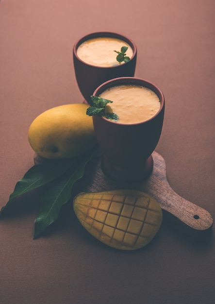 Manga Lassi ou iogurte, popular bebida indiana de verão servida em copo com fruta Alphonso Aam inteira, foco seletivo