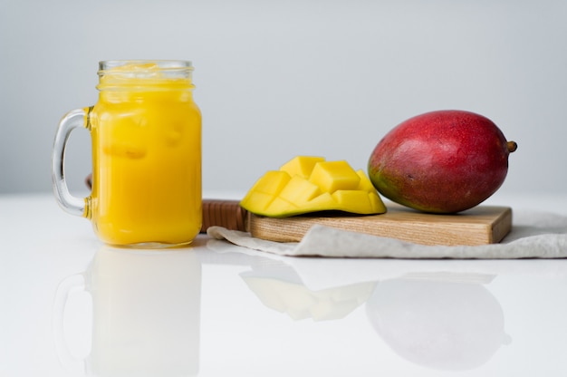 Manga madura e um copo de suco de manga em uma tábua de madeira.