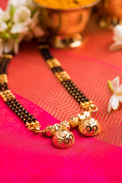 Mangalsutra o collar dorado para usar por una mujer hindú casada, arreglado con sari tradicional con huldi kumkum y flores mogra gajra, enfoque selectivo
