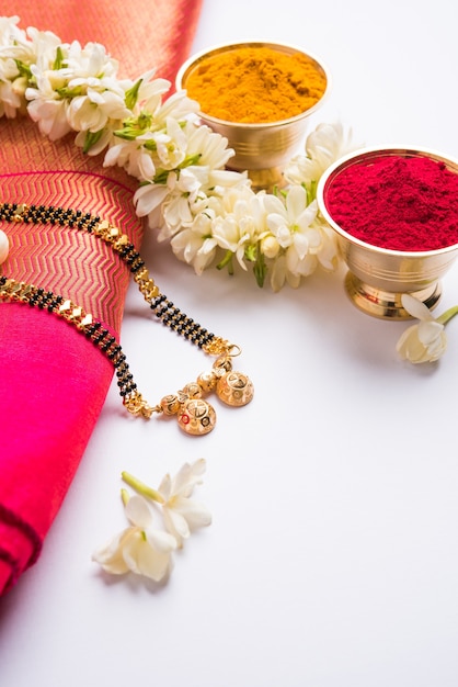 Mangalsutra oder goldene Halskette, die von verheirateten hinduistischen Frauen getragen wird, arrangiert mit traditionellem Saree mit Huldi Kumkum und Mogra-Blumen-Gajra, selektiver Fokus