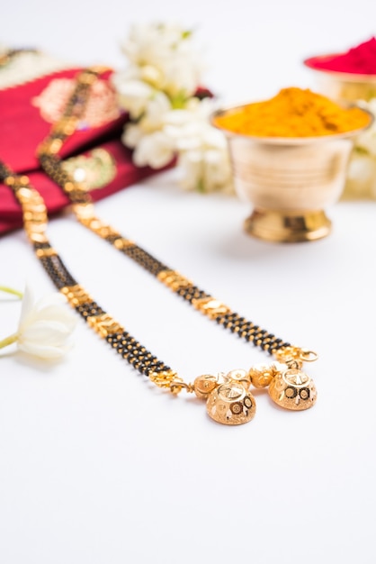 Foto mangalsutra ou colar de ouro para ser usado por mulheres hindus casadas, arranjado com saree tradicional com huldi kumkum e flores mogra gajra, foco seletivo